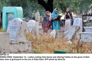 APP34-13 RAWALPINDI: September 13 Ladies reciting Holy Quran and offering Fateha on the grave of their dear ones at graveyard on the eve of Eidul Azha. APP photo by Abid Zia